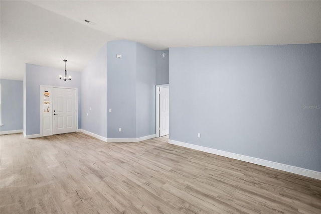 spare room featuring light hardwood / wood-style flooring, a notable chandelier, and lofted ceiling