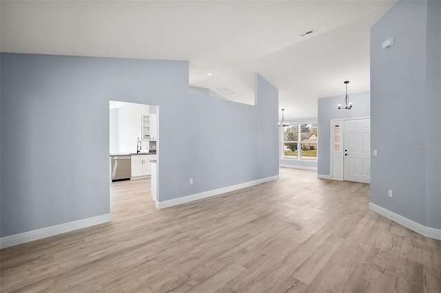 unfurnished living room featuring an inviting chandelier, high vaulted ceiling, and light hardwood / wood-style floors