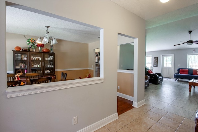 corridor featuring a notable chandelier, a textured ceiling, and light tile patterned flooring