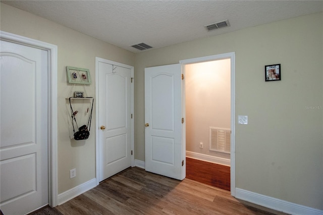 unfurnished bedroom with a closet, dark hardwood / wood-style flooring, and a textured ceiling