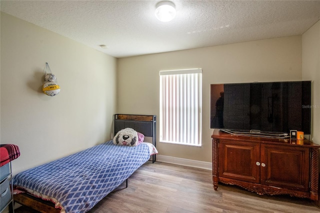 bedroom featuring a textured ceiling and light hardwood / wood-style flooring