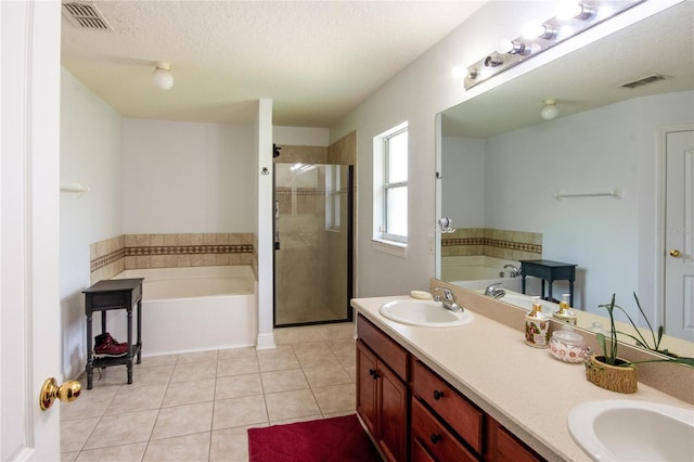 bathroom featuring a textured ceiling, vanity, tile patterned floors, and plus walk in shower