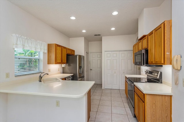 kitchen featuring appliances with stainless steel finishes, sink, a textured ceiling, kitchen peninsula, and light tile patterned flooring