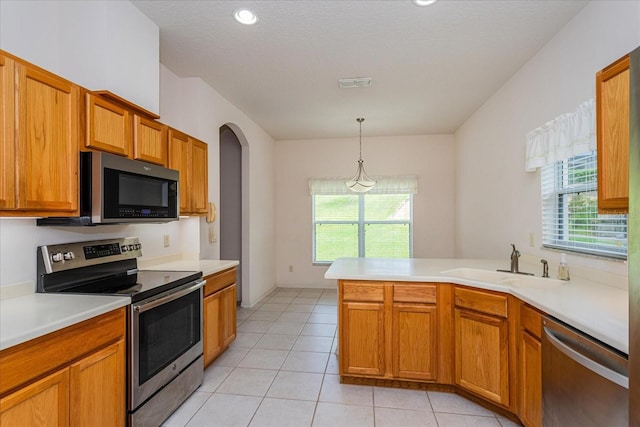 kitchen with appliances with stainless steel finishes, sink, pendant lighting, light tile patterned floors, and kitchen peninsula