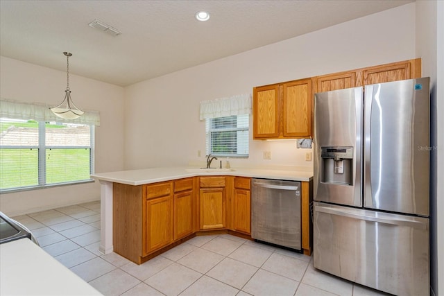 kitchen featuring sink, hanging light fixtures, appliances with stainless steel finishes, and light tile patterned flooring