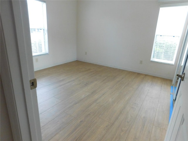 empty room with plenty of natural light and light hardwood / wood-style floors