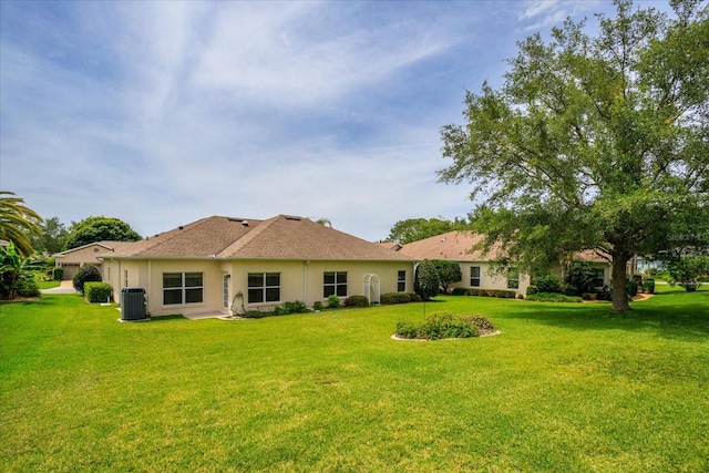 rear view of property with central AC and a yard