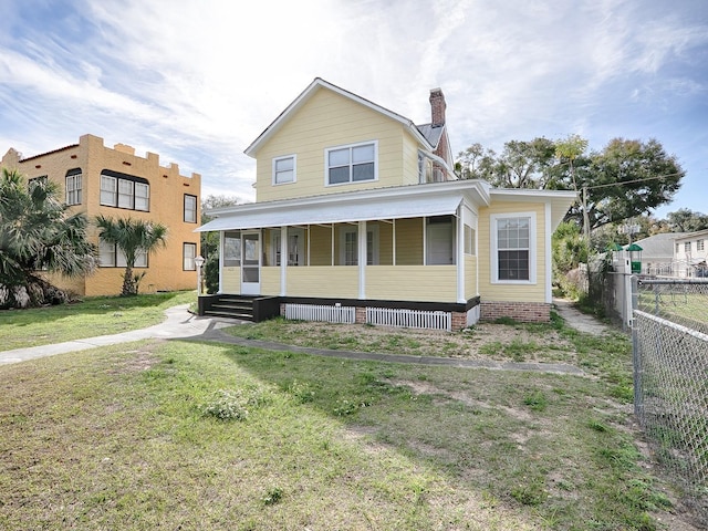 rear view of house with a lawn and covered porch