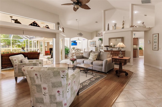 living room with light tile floors, high vaulted ceiling, and ceiling fan with notable chandelier