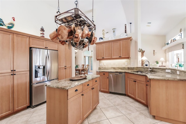 kitchen with sink, a kitchen island, appliances with stainless steel finishes, light tile flooring, and light stone countertops