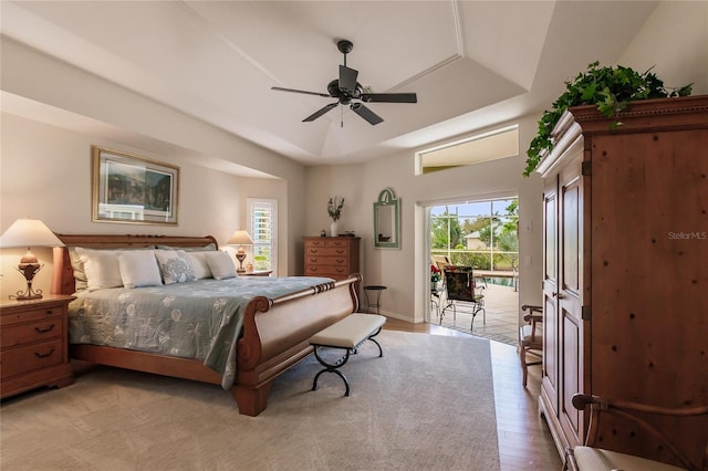 bedroom with access to outside, ceiling fan, a raised ceiling, and light wood-type flooring