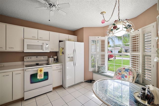 kitchen featuring white appliances, light tile floors, hanging light fixtures, white cabinets, and ceiling fan with notable chandelier