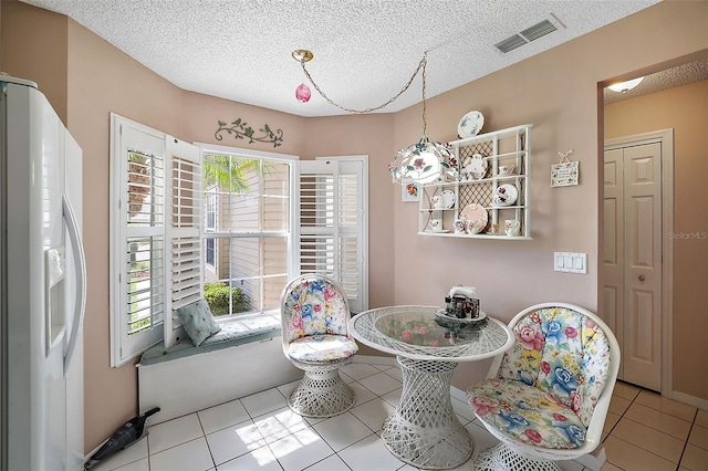 dining room featuring light tile flooring, a textured ceiling, and a wealth of natural light