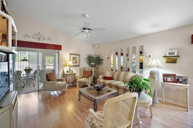 living room featuring a textured ceiling, vaulted ceiling, ceiling fan, and light wood-type flooring