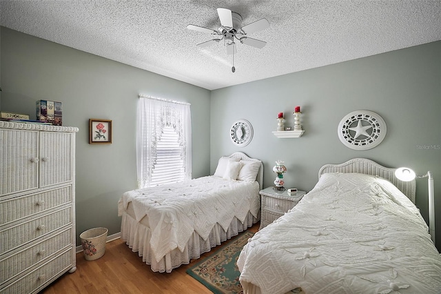 bedroom with a textured ceiling, wood-type flooring, and ceiling fan