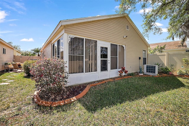 rear view of property with central AC unit and a lawn