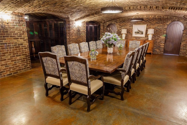 dining room featuring lofted ceiling, brick wall, and brick ceiling