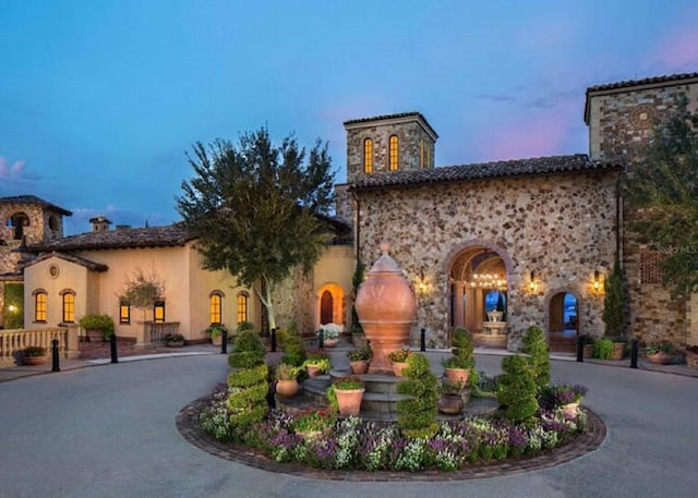 exterior space featuring curved driveway, a chimney, and stucco siding