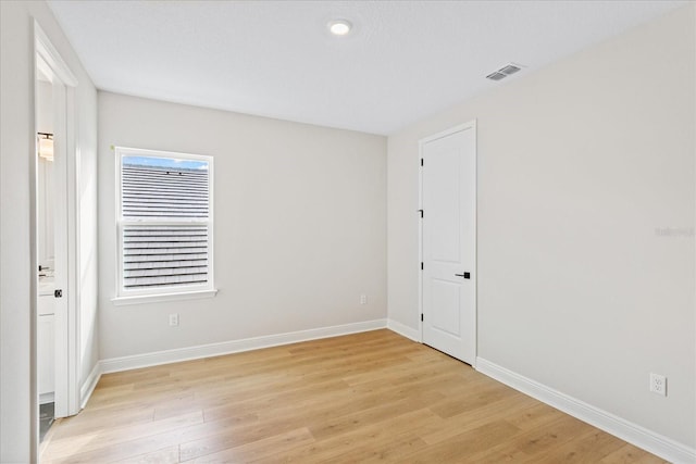 empty room featuring visible vents, light wood-style flooring, and baseboards