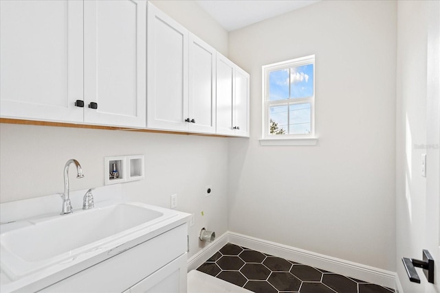 washroom with hookup for a washing machine, cabinet space, hookup for an electric dryer, a sink, and baseboards