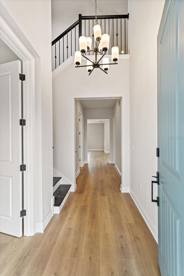 entryway with stairway, light wood-type flooring, a towering ceiling, and baseboards