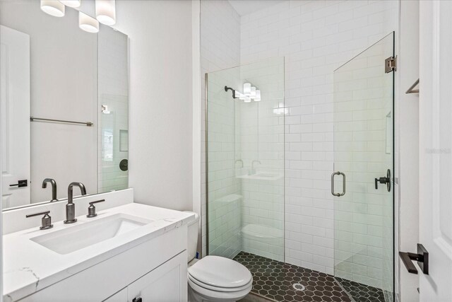 bathroom with a shower with shower door, toilet, and vanity with extensive cabinet space