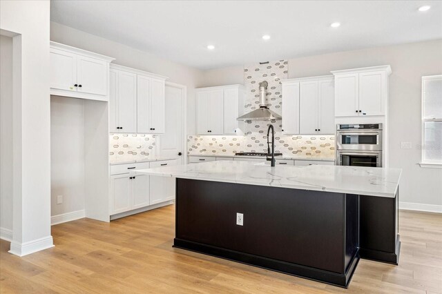 kitchen with white cabinetry, backsplash, wall chimney exhaust hood, and stainless steel appliances