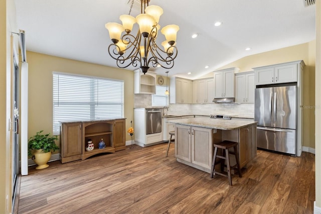 kitchen featuring appliances with stainless steel finishes, pendant lighting, a kitchen island, and a kitchen breakfast bar