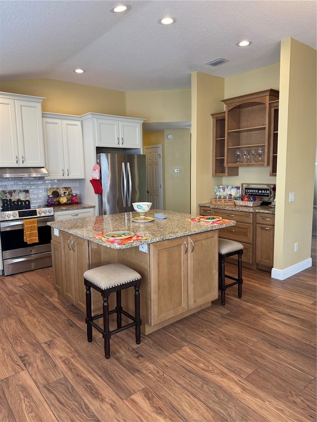 kitchen with a breakfast bar area, white cabinets, stainless steel appliances, and a center island