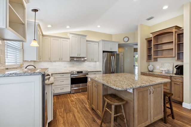 kitchen with hanging light fixtures, stainless steel appliances, a center island, white cabinets, and a kitchen bar