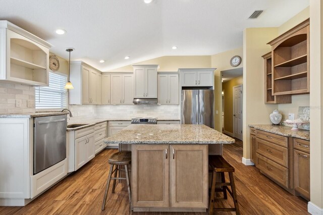 kitchen with white cabinetry, a center island, appliances with stainless steel finishes, and a breakfast bar