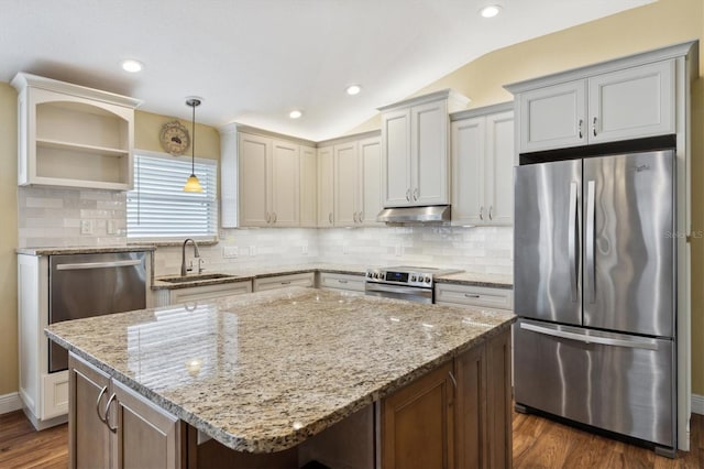 kitchen with stainless steel appliances, light stone countertops, vaulted ceiling, a kitchen island, and sink