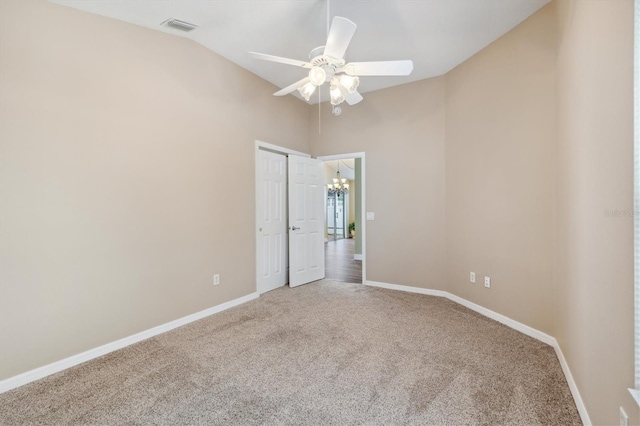 carpeted empty room featuring high vaulted ceiling and ceiling fan with notable chandelier