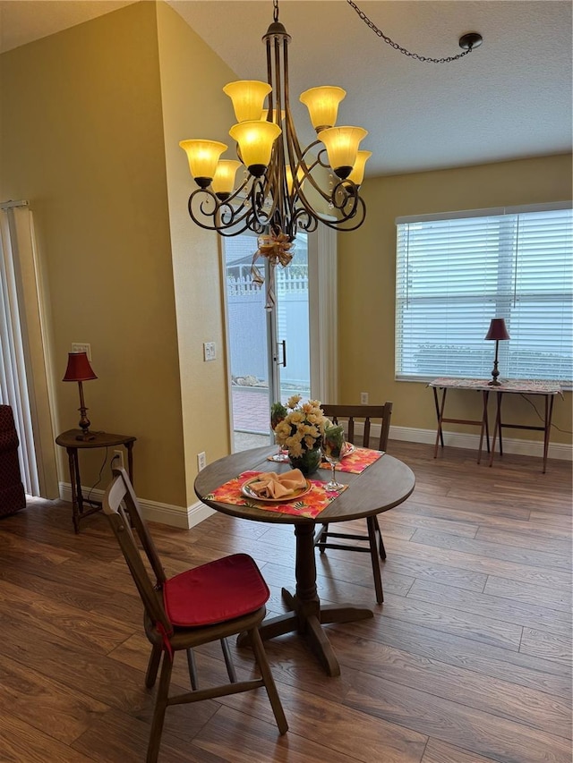 dining space with a notable chandelier, dark wood-type flooring, and a healthy amount of sunlight