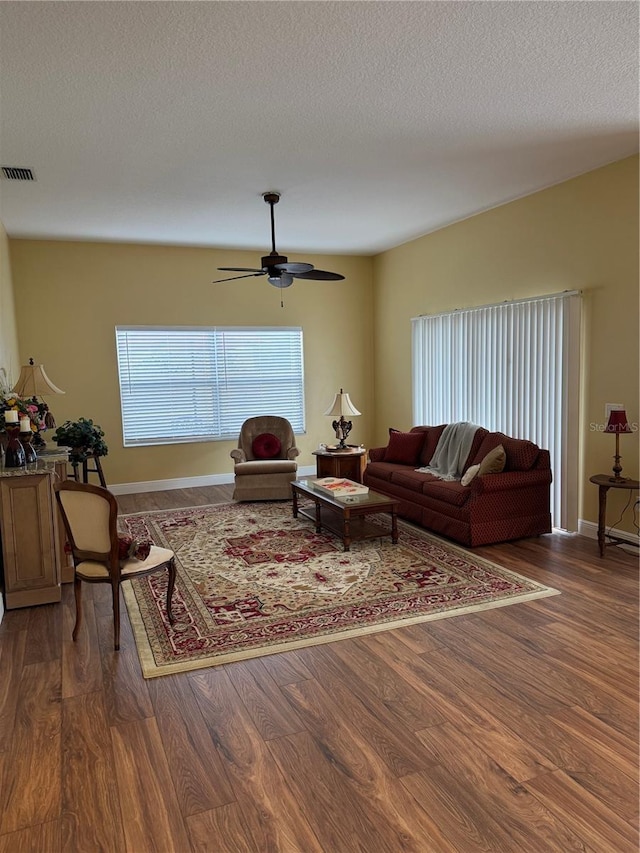 living room with ceiling fan, dark hardwood / wood-style floors, and a textured ceiling