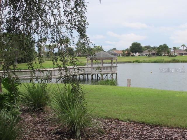 view of dock featuring a gazebo, a water view, and a lawn