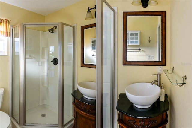 bathroom featuring a shower with door, vanity, and toilet