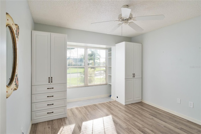 unfurnished bedroom featuring a textured ceiling, ceiling fan, fridge, and light wood-type flooring