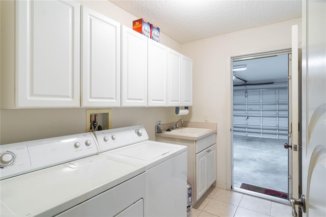 laundry room with cabinets, a textured ceiling, sink, light tile patterned floors, and separate washer and dryer