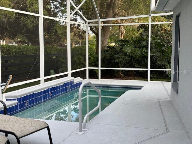 view of pool featuring glass enclosure and a patio