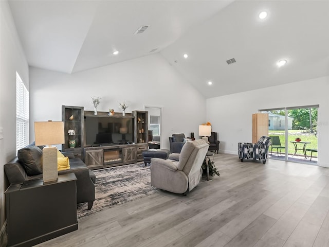 living room with high vaulted ceiling and light hardwood / wood-style flooring