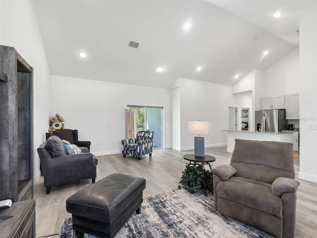 living room with high vaulted ceiling and light wood-type flooring