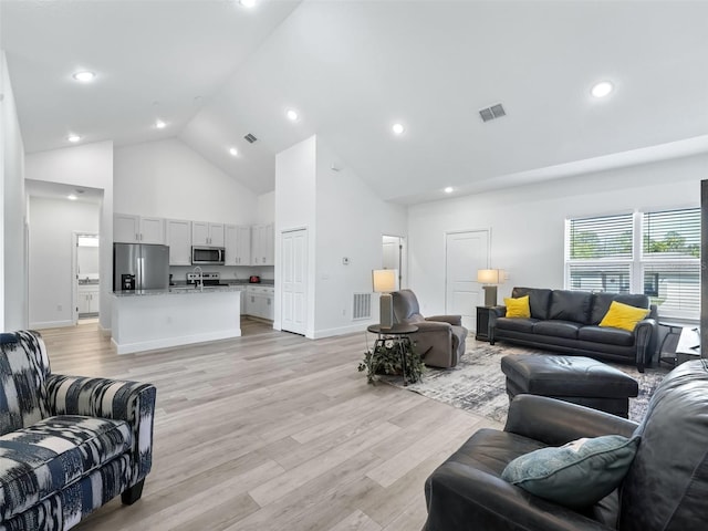 living room with high vaulted ceiling and light wood-type flooring