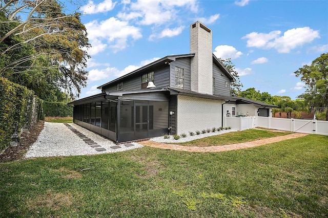 rear view of property featuring a sunroom and a lawn