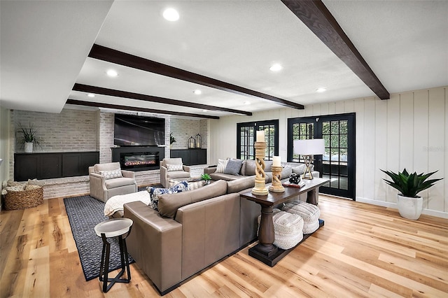 living room with brick wall, light hardwood / wood-style floors, french doors, and beam ceiling