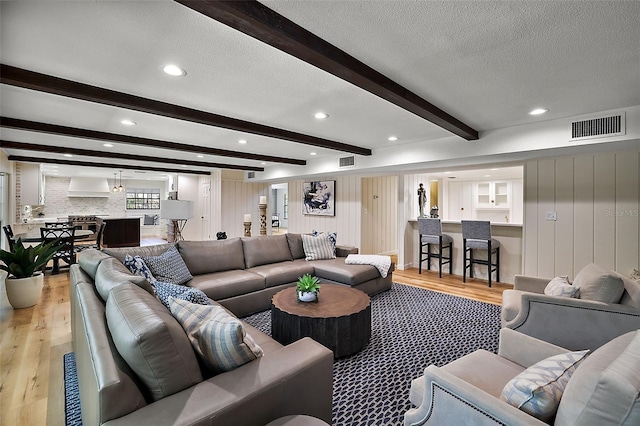 living room with light hardwood / wood-style floors, beam ceiling, and a textured ceiling