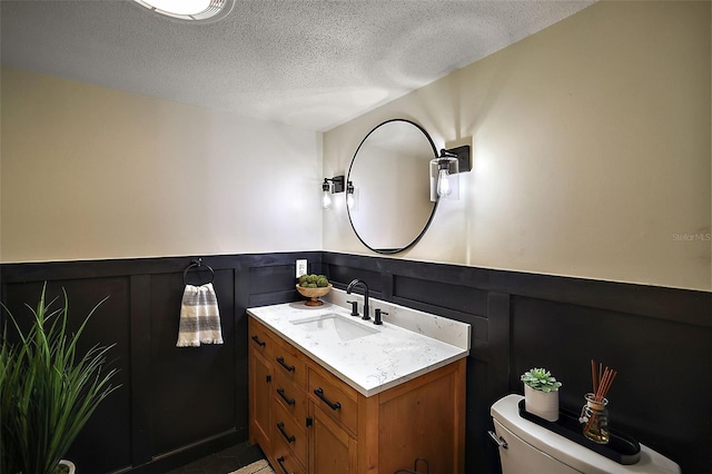 bathroom featuring a textured ceiling, vanity, and toilet