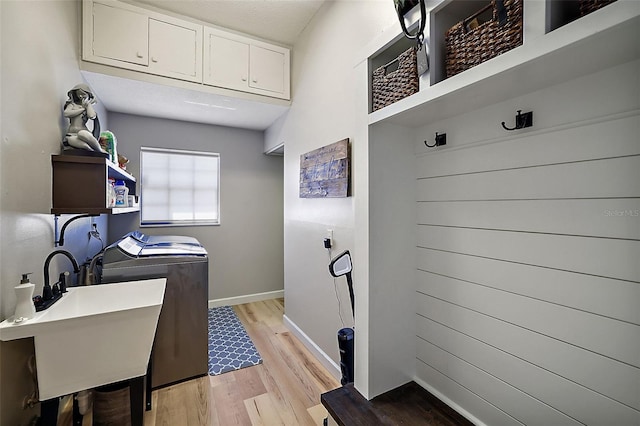 laundry room with sink, light hardwood / wood-style flooring, cabinets, and washer and clothes dryer