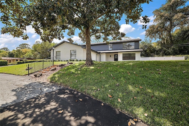 view of front facade with a front yard, fence, and stucco siding