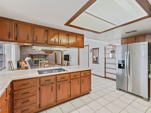 kitchen featuring black electric cooktop, a brick fireplace, light tile floors, and stainless steel refrigerator with ice dispenser